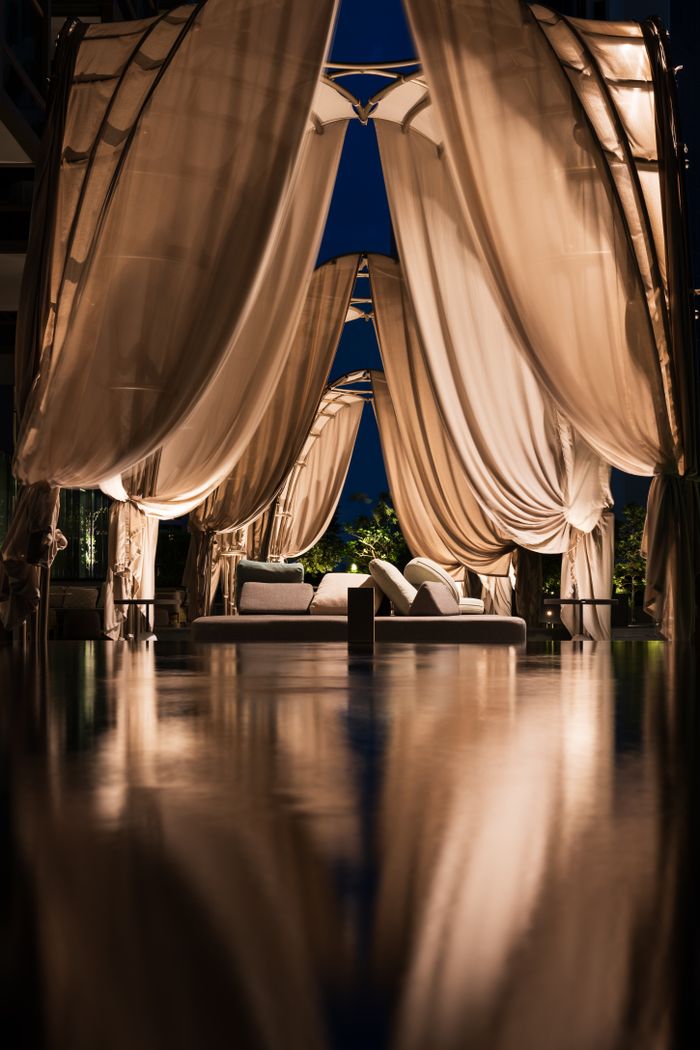 Services Elegant cabana with flowing curtains and ambient lighting, creating a serene nighttime atmosphere in Singapore.
